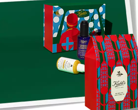 Kiehl's promotional banner featuring holiday gift sets and skincare products against a green background.