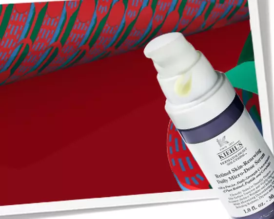 Kiehl's promotional banner featuring Retinol Serum and the text "Age-Less Essentials" against a festive red and green background.