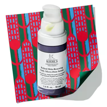 Kiehl's Retinol Skin- Renewing Daily Micro-Dose Serum bottle with a dollop of serum on the pump, resting on a patterned holiday background. 